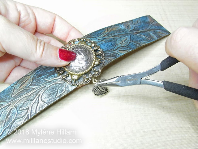 Using pliers to attach the charms to the filigree