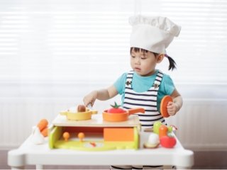 Little girl pretend playing to be a chef is cooking in her toy kitchen