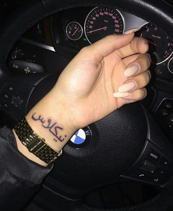 chica conduciendo un bmw , lleva en la muñeca un tatuaje arabe
