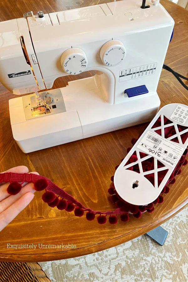 Sewing manchine and red pom pom trim on table