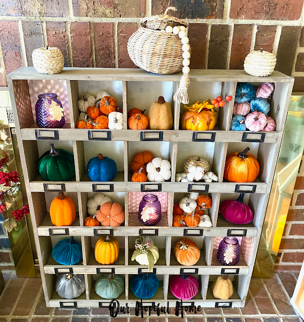 mini velvet pumpkins in wooden cubby shelf