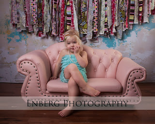 Girl in blue romper on a pink couch