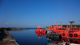 Punaisia veneitä satamassa, aurinkoisessa, tyynessä säässä. 