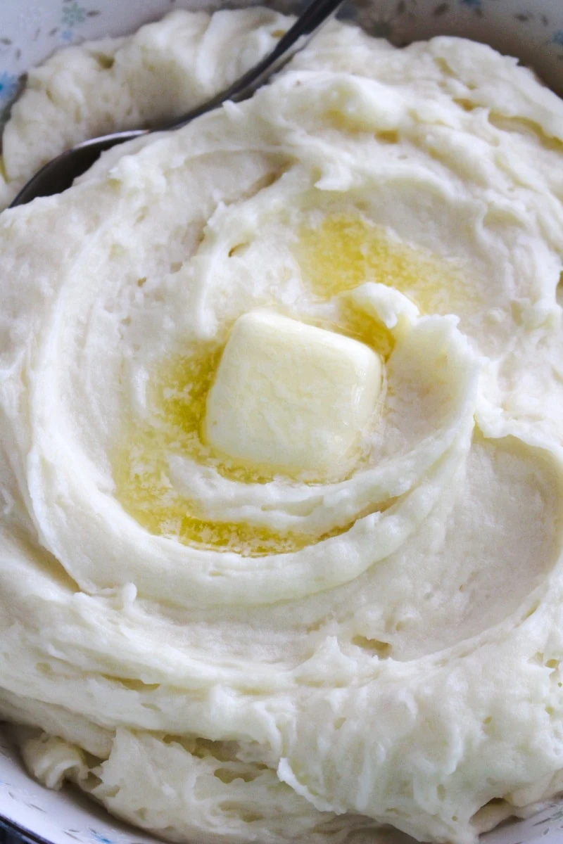 Top view closeup of mashed potatoes in a white bowl with smal blue flowers.