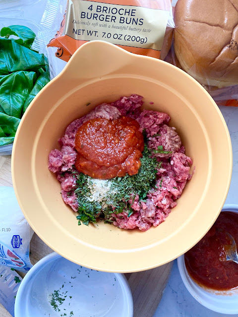 Yellow mixing bowl of burger ingredients and sides.