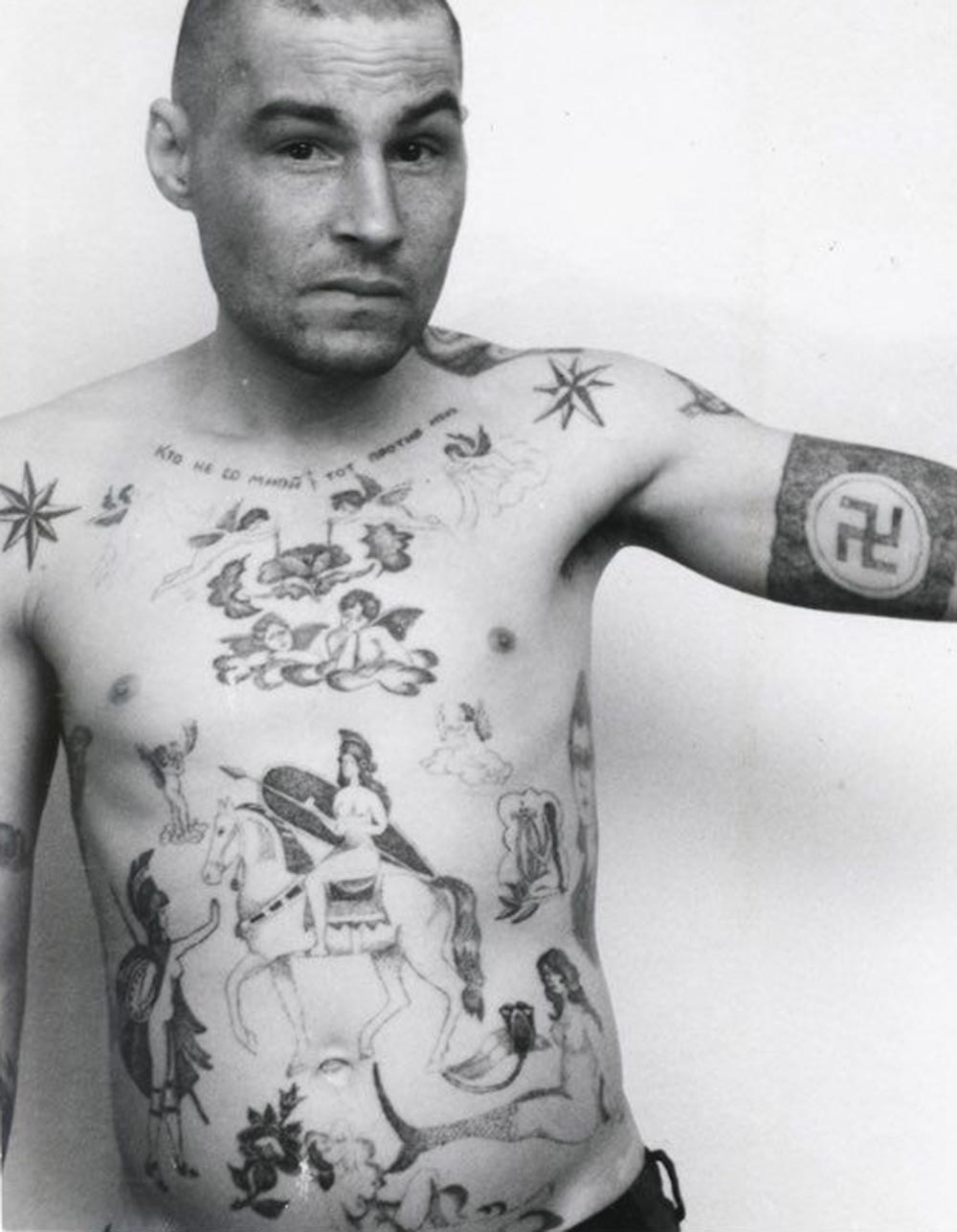 Text across the chest reads 'He who is not with me is against me.' The swastika and Nazi symbols may mean the owner has fascist sympathies, though they are more usually made as a protest and display of aggression toward the prison or camp administration. During the Soviet period the authorities often removed these tattoos by force either surgically or by using an etching method. A tattoo of a mermaid can indicate a sentence for rape of a minor, or child molestation. In prison jargon the nickname for a person who commits this type of crime is 'amurik,' meaning 'cupid', 'shaggy,' or a universal 'all rounder.' They are 'lowered' in status by being forcibly sodomised by other prisoners, sometimes in groups.