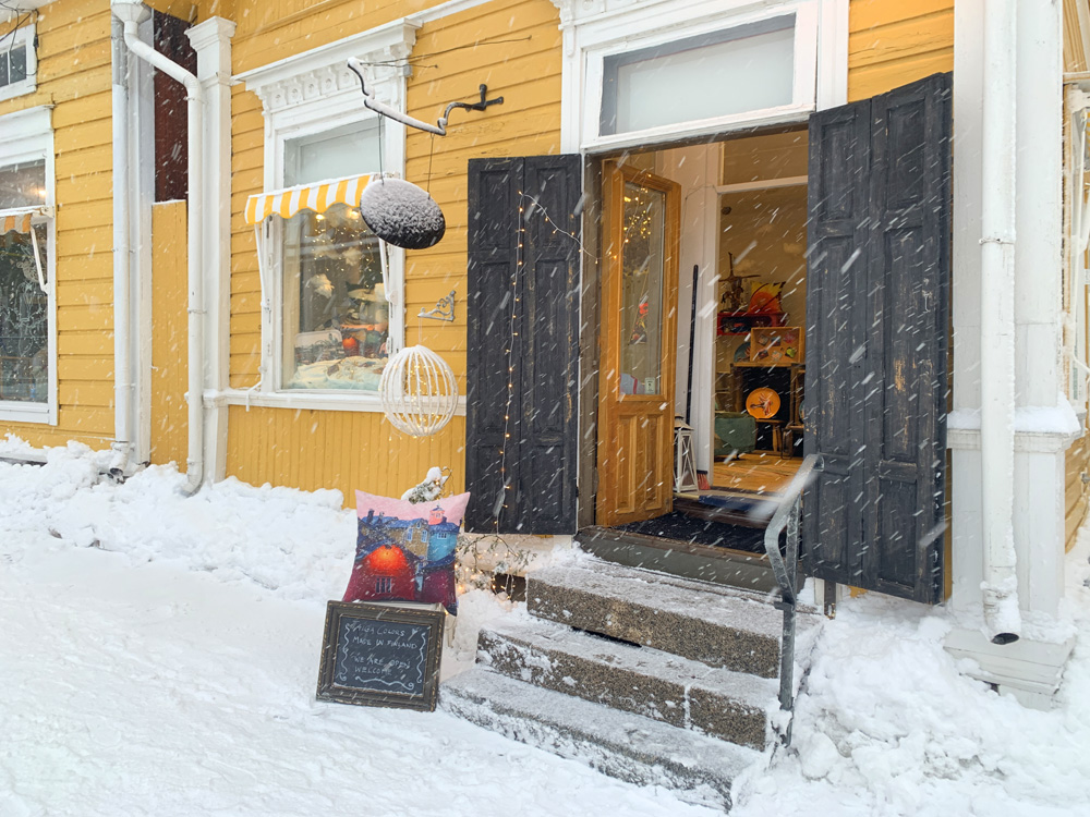 Shop front in a yellow house, with a cushion outside