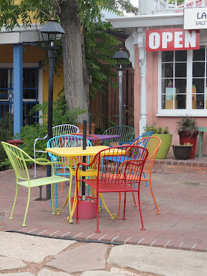 colored metal chairs at an outdoor cafe; sign says OPEN