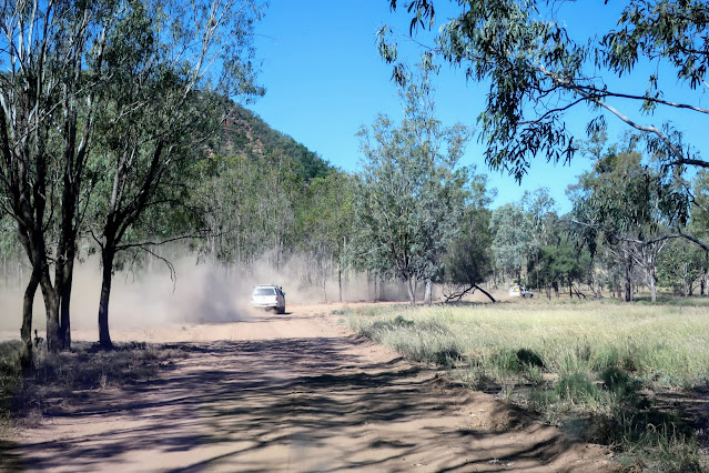 Cars kicking up dust on dirt road