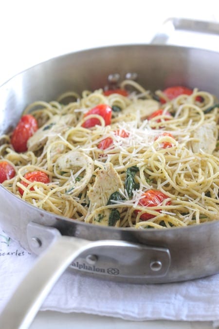 Skillet filled with pasta, tomatoes, spinach leaves for a summer pasta dinner kids will love