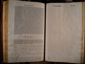 An open book. The lefthand page is filled with printed text and handwritten notes. The righthand page is blank.