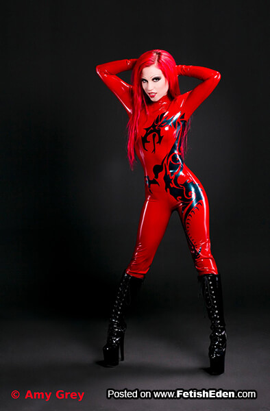Red latex catsuit Amy Grey has red hair and long black PVC boots
