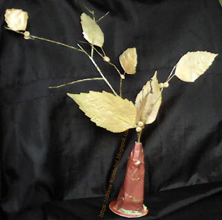 o crenguta vopsita cu auriu si frunze lipite vopsite tot cua auriu, in suport de carton maro
