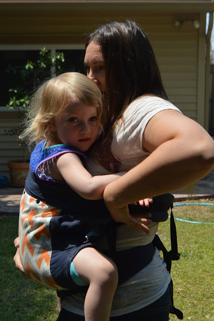 Momma is seen pulling gently on the shoulder strap webbing to tighten the carry