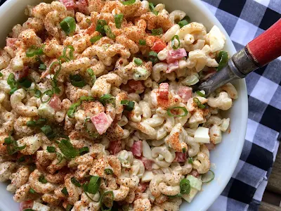 Top view of a bowl of picnic macaroni salad with a serving spoon.