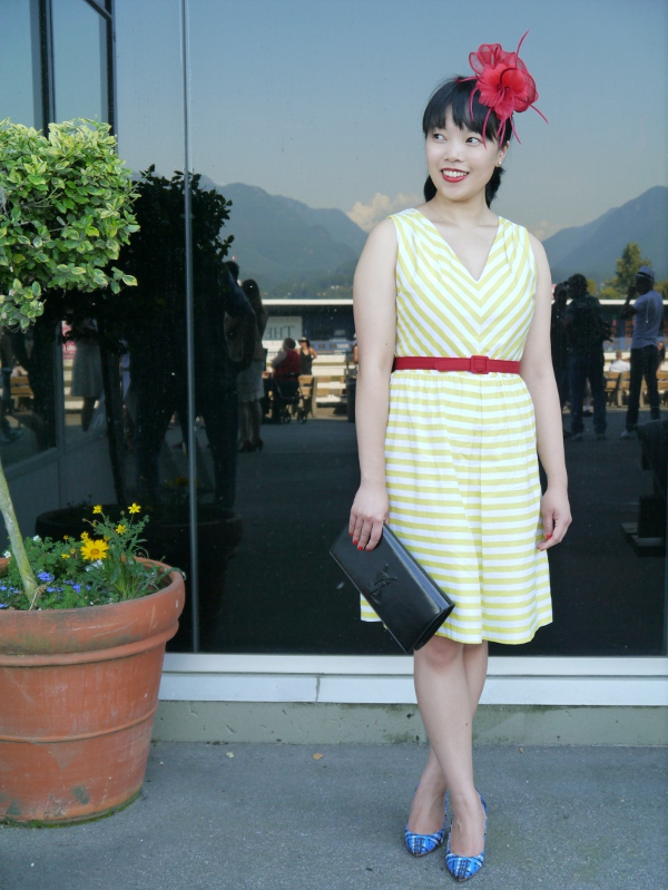 Vancouver blogger Lisa Wong of Solo Lisa wears a yellow-and-white striped day dress from JACOB, a red fascinator from Fine Finds, and a red belt along with a Saint Laurent 'Belle de Jour' black patent clutch and patterned cobalt-and-blue J. Crew 'Everly' pumps.