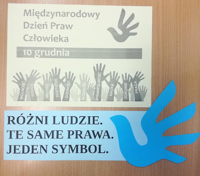 Brązowe tło żółta kartka napis Międzynarodowy Dzień Praw Człowieka niebieska kartka napis Różni ludzie Te same prawa Jeden symbol 1  niebieski ptak z papieru