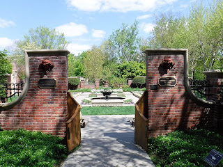 an open gate in an ornate brick wall reveals a victorian garden at Lauritzen Gardens in Omaha