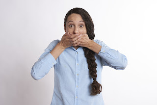 Girl with braid holding hand over own mouth