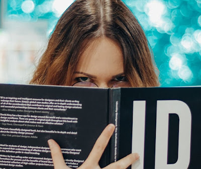 Woman looking over top of open book