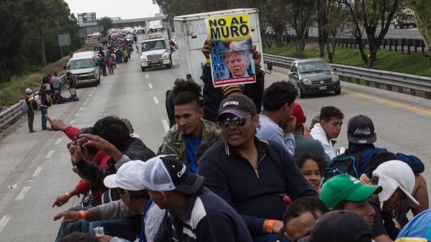 A Central American migrant holds a sign with a message that reads in Spanish: "No to the wall Trump", while hitching a ride on a truck in Tepotzotlan, Mexico, Saturday, Nov. 10, 2018