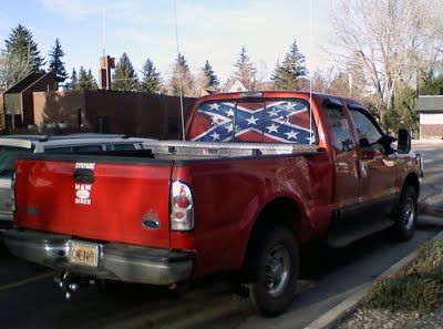 Large red truck, confederate flag in back window, two skull and crossbones bumperstickers, one bumpersticker saying 'Bad ass boys drive bad ass toys,' and one unreadable sticker