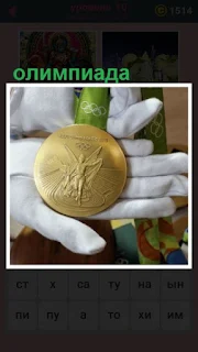  в руках лежит медаль, которую заработал спортсмен на олимпиаде