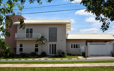 A elevação lateral da casa conta com um grande painel de blocos de vidro sobre uma porta de correr que atua como acesso secundário da edificação.