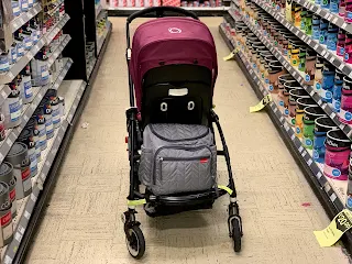 A pushchair in a DIY paint aisle with the Skip Hop changing bag on the back