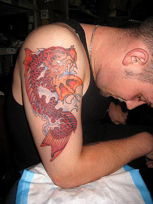  red koi tattoo design in the splashing water on a white boy upper arm