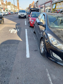 Some white lines and a bicycle symbol (offset to the left) painted on Portland Road. Amongst many cars.