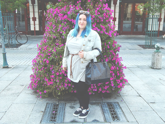 Girl with blue hair standing in front of purple folowers