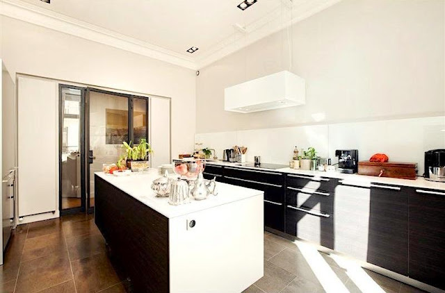 kitchen with wood fronts, no upper cabinets, white counter tops, island and large square tiles