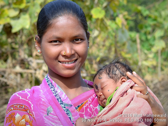 double portrait; duo portrait; mother and baby; mother and child; tribal; Adivasi; Matt Hahnewald Photography; Facing the World; photography; photo; image; face perception; physiognomy; psychological; outstanding; favourite; superior; beautiful; Nikon D3100; Nikkor AF-S 50mm f/1.8G; prime lens; 50mm lens; 4 : 3 aspect ratio; horizontal format; street; portraiture; portrait; closeup; outdoor; colour; cultural; character; personality; real people; human head; human face; human eyes; nose; smiling eyes; mouth; smiling; teeth; facial expression; eye contact; bareheaded; consent; empathy; rapport; respect; encounter; relationship; ethnic portrait; Kuvi Kondh tribe; Upper Bombu; Orissa; East India; modern Adivasi; female; young adult; posing; happy; pretty; soulful; nose stud; earrings; villager; seven-eighths view; tribal Madonna; Christian