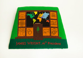 A needlepoint seat cover reading "James Wright, 16th president" and showing a podium world map, among other images.