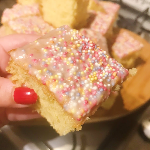 slice of school sponge cake held up over rest of cake on chopping board