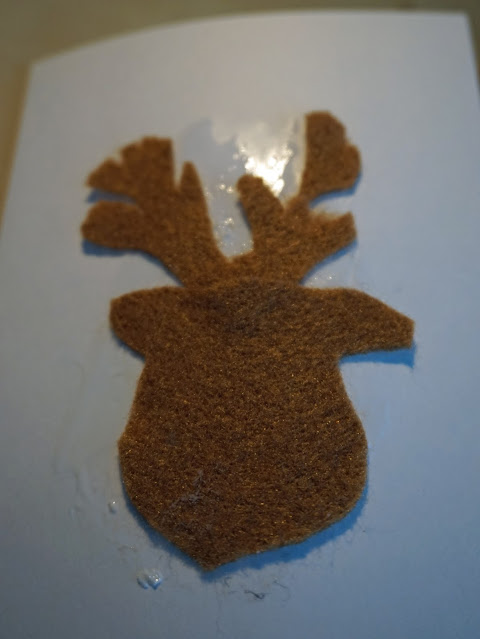 A glued on brown felt cut out Reindeer head, on a white blank greetings card