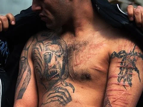Imagen de un hombre cubriendo a otro con chaqueta Tapando tatuajes por estra prohibidos
