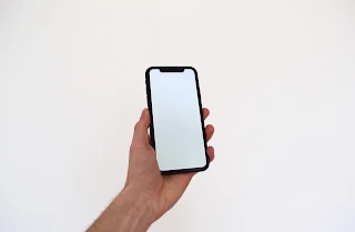 A person holding a iPhone X with a white screen.