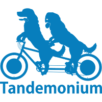 Tandemonium's logo: a light blue silhouette of two dogs riding a tandem bicycle, over the word Tandemonium