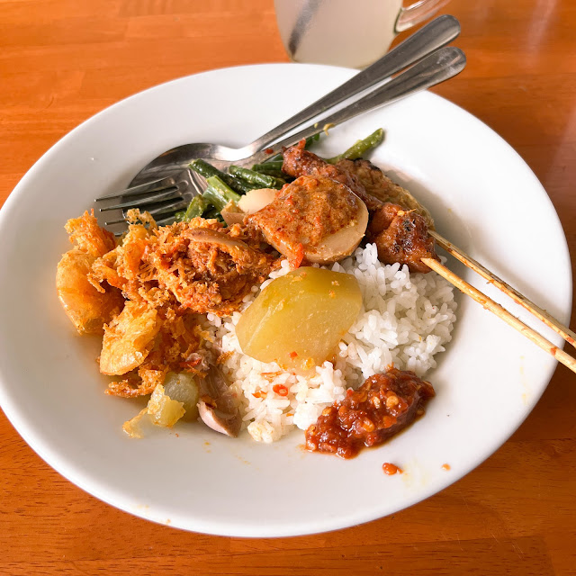 Nasi campur Bali dengan nasi putih, telur rebus, ayam suwir, udang goreng, dendeng, kentang goreng, sate tusuk, sate lilit, dan tumis kacang panjang