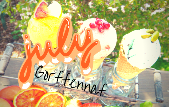 'July - Gorffennaf' with ice-cream and fruit on a table behind the words