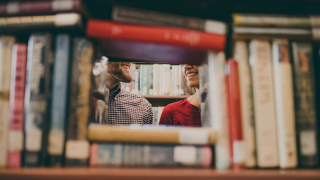 a couple seen through a bookshelf
