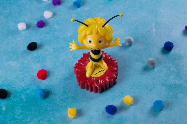 A plastic maya the bee character, standing on a red flower