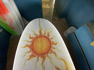 Painting the sun on a surfboard by Paul Carter