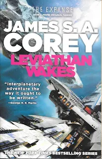 Leviathan Wakes Cover (in a dark-blue star field, the metallic hull of a vast spaceship looms into view while an astroid drifts in the distance)