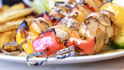 Tofu and vegetable kebabs on a plate with potato wedges.