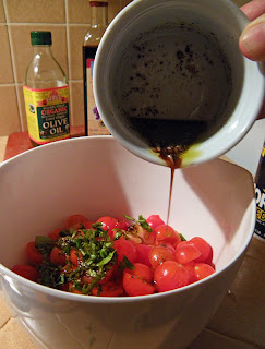 Husband's hand pouring dressing into bowl with tomatoes and basil