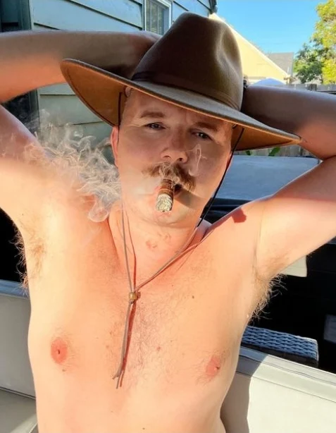 Arm stretched above head wearing a tan hat cigar and mouth handsome Daddydoescigars