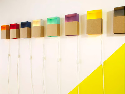 Boîtes à lumière colorées en carton recyclé de la marque ¿adónde? accrochées au mur.